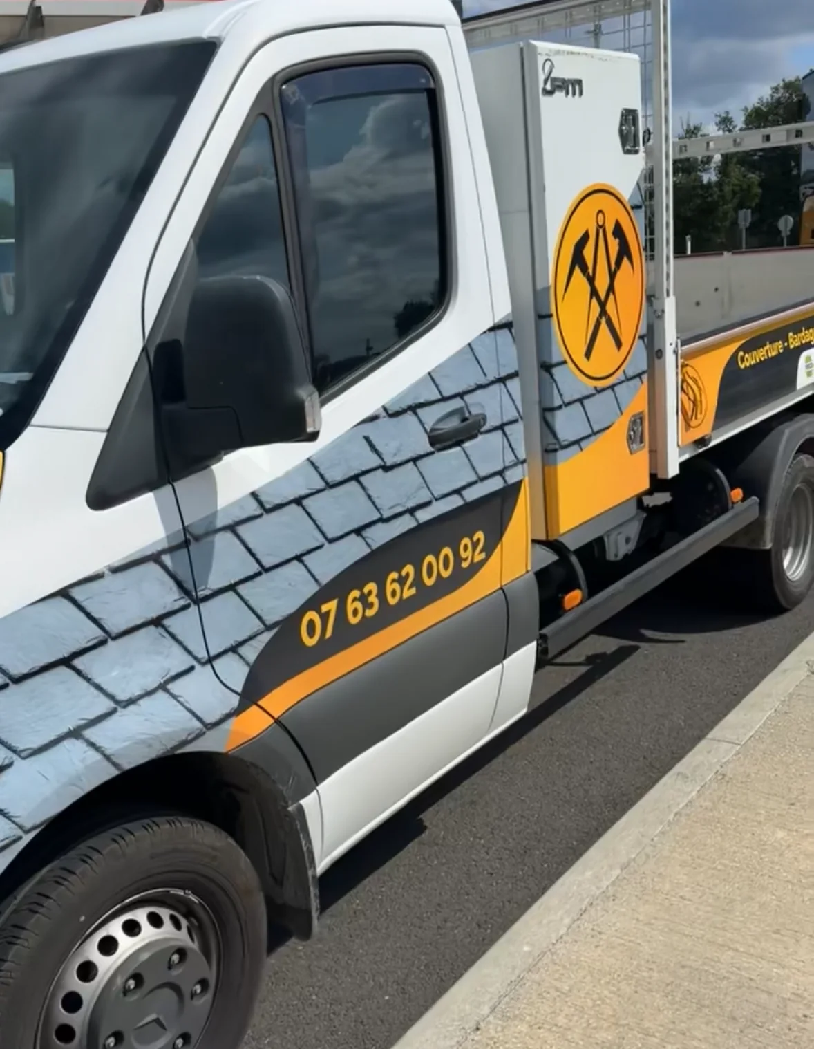 Camion de l’entreprise avec son marquage orange, noir et ardoise